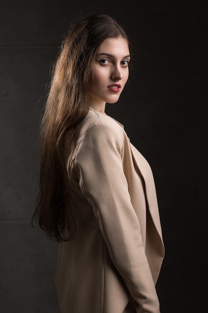 Portrait of a young brunette with long hair in the studio Dramatic photo in dark colors