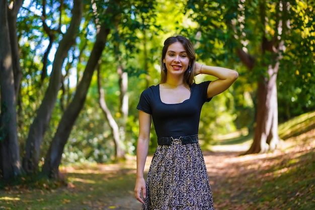 Portrait of a young brunette woman in nature walking in the natural park in autumn