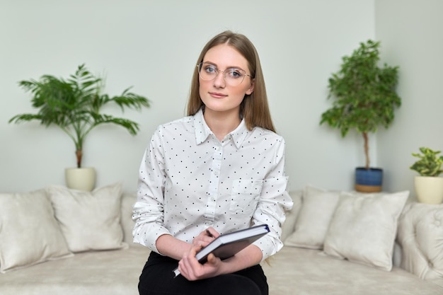 Portrait of young business woman in glasses with business notebook