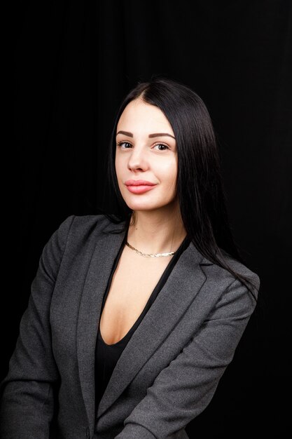 Portrait of young business woman in  a grey jacket on black.