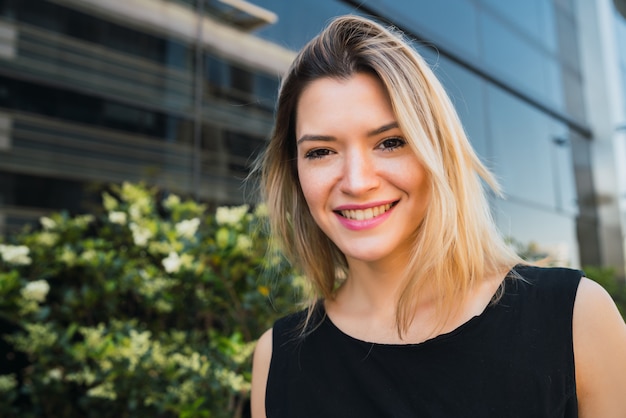 Portrait of young business woman standing outside office buildings. Business and success concept.