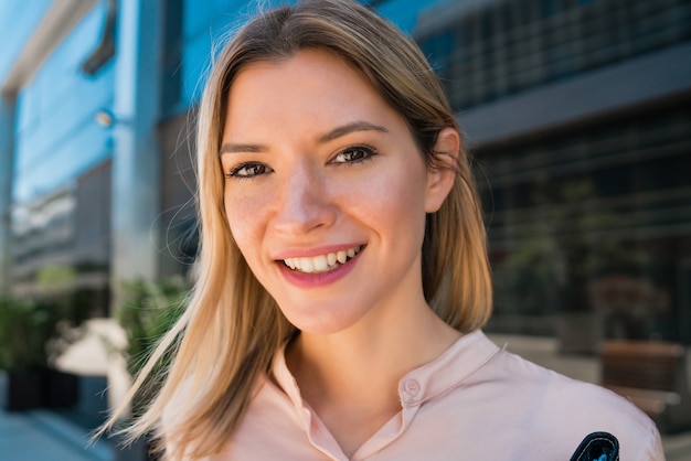 Portrait of young business woman standing outside office buildings. Business and success concept.