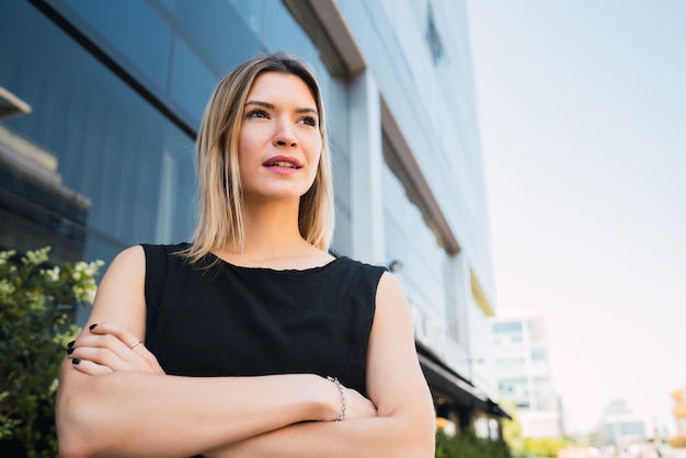 Portrait of young business woman standing outside office buildings