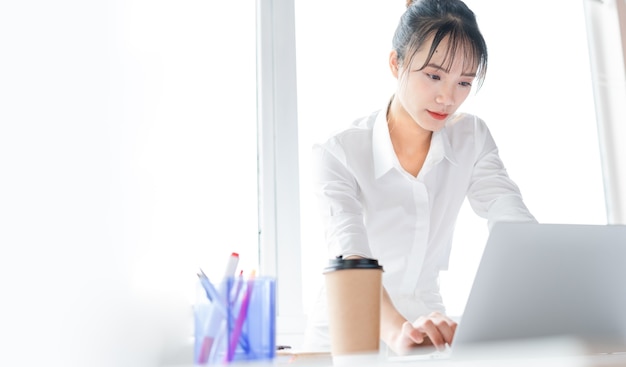 Portrait of young business woman standing and working together with laptop