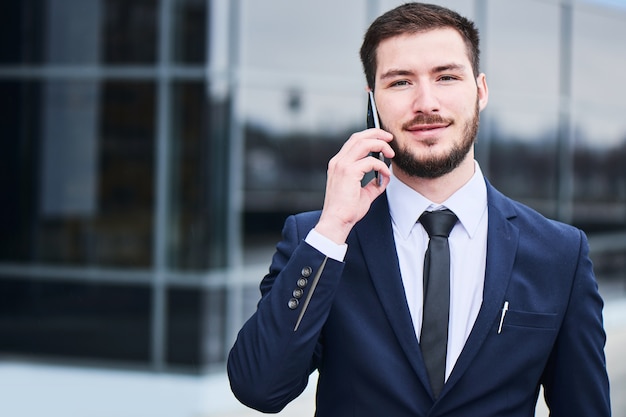 Portrait of a young businessman in a blue suit talking on a cell phone