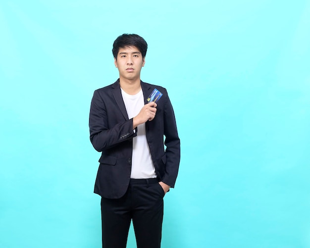 Portrait of young businessman Holding and showing credit card on hand on Isolated blue background