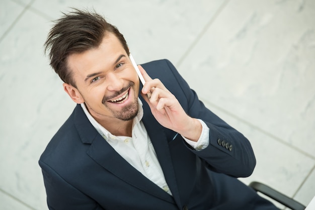 Portrait of young businessman is speaking by phone.