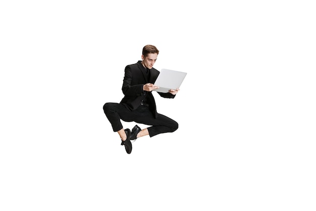 Portrait of young businessman in a jump with laptop isolated over white background