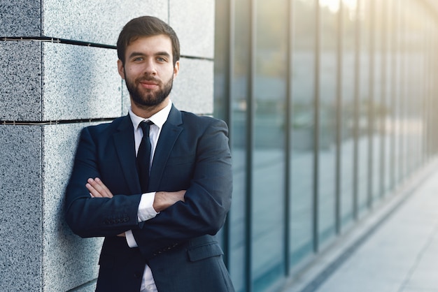 Portrait of young businessman in a suit  posing on background of office building 