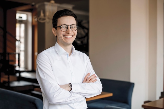 Portrait of a young businessman that is posing and smilling in a fancy office.