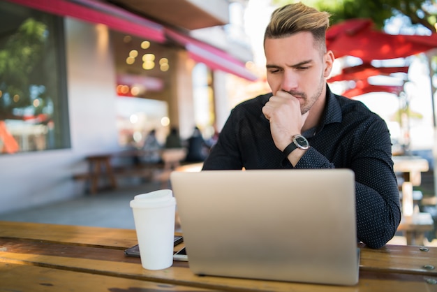 Portrait of young businessman working on his laptop while sitting in a coffee shop