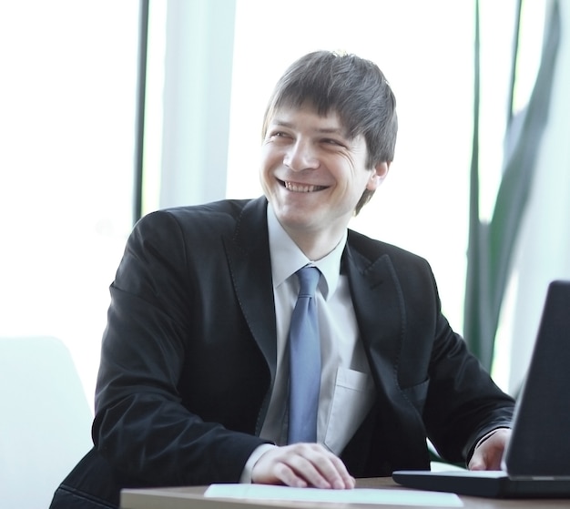 Portrait of a young businessman on workplace in the office.