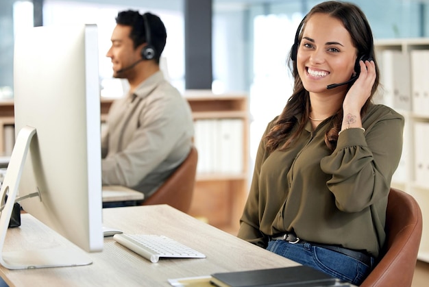 Portrait of a young businesswoman using a headset and computer in a modern office