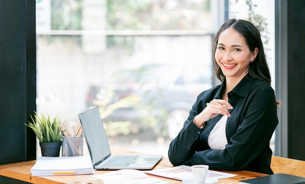 Portrait of young businesswoman using laptop and documents on the table at office