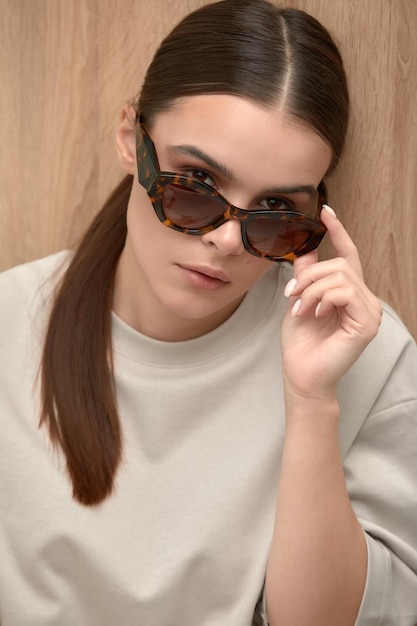 Portrait of a young calm woman in glasses looking through glasses at the camera shot of a young business woman in glasses stylish glasses fashion accessory