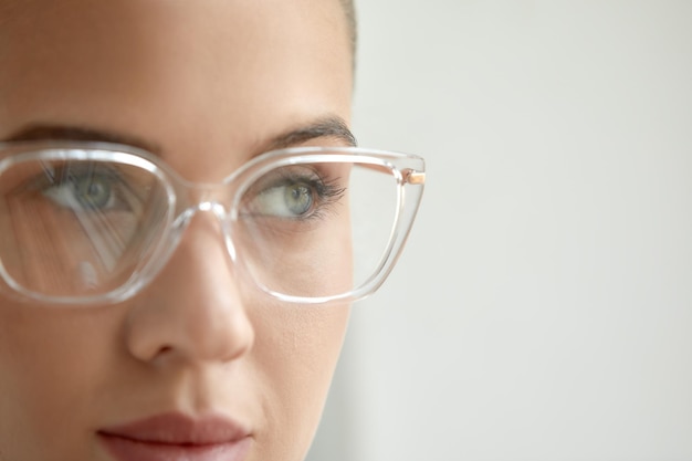 Portrait of a young calm woman in glasses looking through glasses at the camera shot of a young business woman in glasses stylish glasses fashion accessory