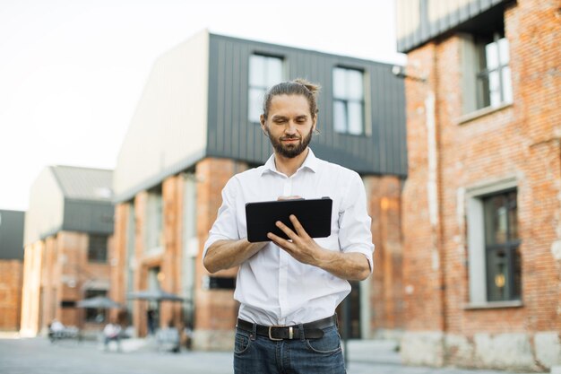 Photo portrait of young caucasian businessman using tablet in city