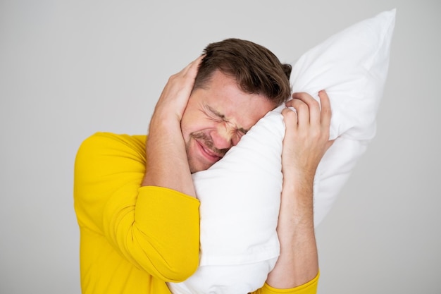 Portrait of Young Caucasian man in bed angry about noise