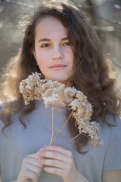 Portrait of a young caucasian woman. Happy beautiful curly girl close-up, wind fluttering hair. Spring portrait outdoors.