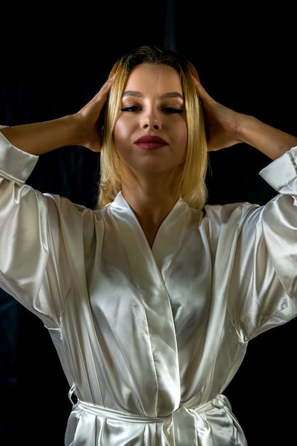 Portrait of young charming woman in silk robe on wooden studio chair posing isolated on green background concept of a portrait of a beautiful girl