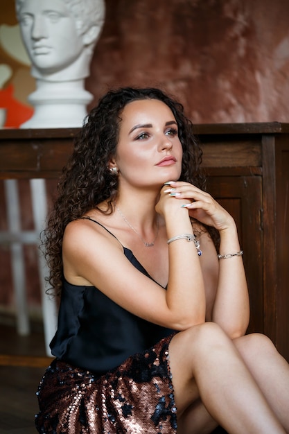 Portrait of a young charming woman with curly hair, fair-skinned girl in a black top and with a smile on her face