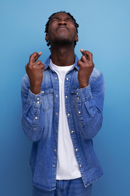 Portrait of a young cheerful american man with dreadlocks in a denim jacket who screwed up