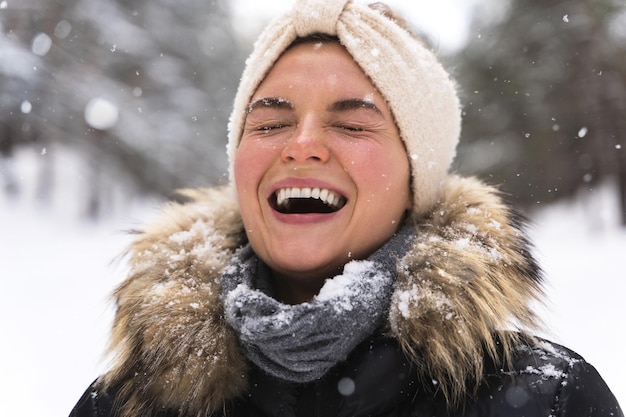 Portrait of young cheerful girl enjoying snowfall during beautiful winter day