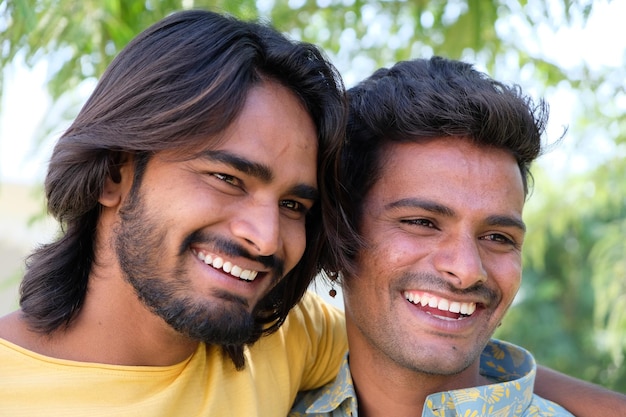 Portrait of a young cheerful Indian gay couple embracing and smiling in a park