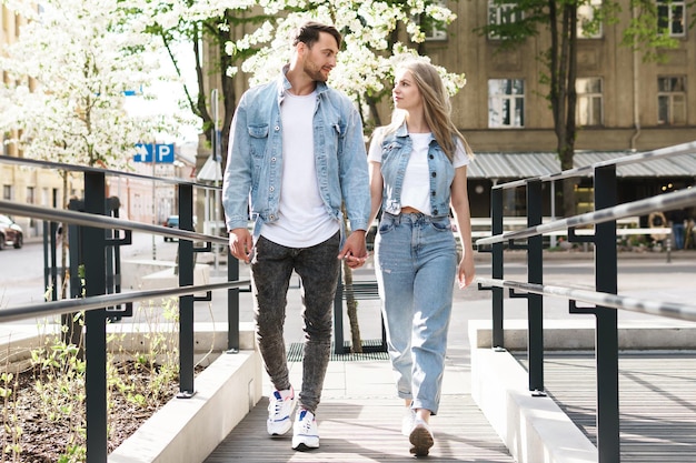 Portrait of young confident and loving couple wearing denim outfits walking during their date on a city street