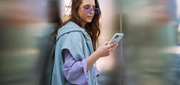 Portrait of young cool woman holding smartphone sending text messages high quality photo