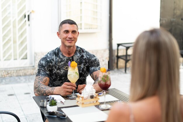 Portrait of Young Couple Drinking Cocktails in Restaurant Outdoors and Enjoying Time