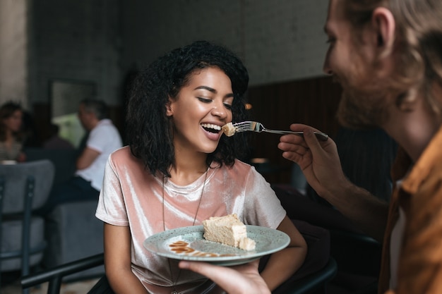 Portrait of young couple eating cake in restaurant