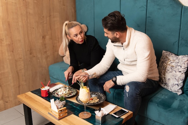 Portrait of Young Couple Eating Pancakes in Restaurant and Drinking Cocktail Chill and Colada