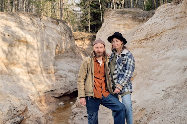 Portrait of young couple of hikers looking at camera while travelling together outdoors among the rocks