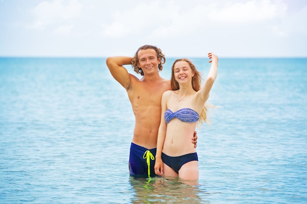 Portrait of young couple in love at beach and enjoying time being together. Young couple having fun on a sandy coast.