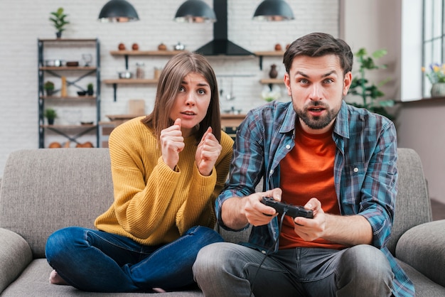 Portrait of young couple playing video game at home