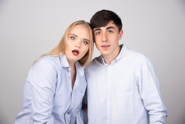 Portrait of a young couple standing together isolated over gray wall.