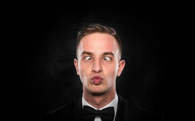 Portrait of a young cross-eyed businessman with funny face over dark background.