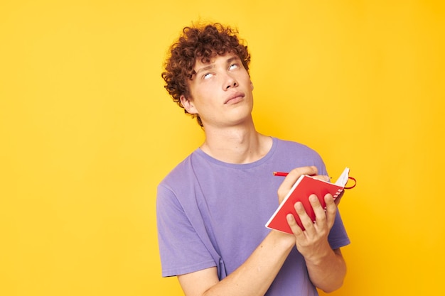 Portrait of a young curly man notepad with pen learning emotions isolated background unaltered