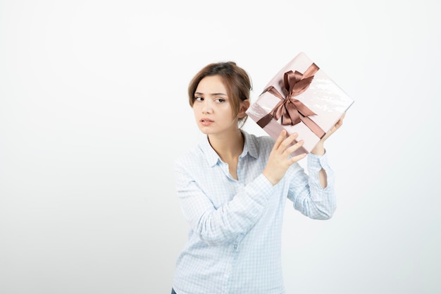 Portrait of a young cute girl holding present box with ribbon. High quality photo