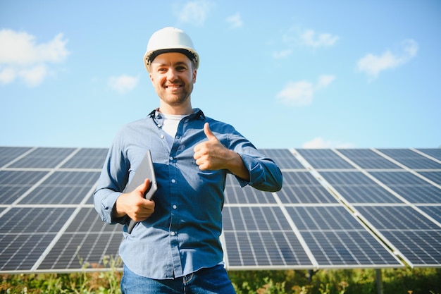 The portrait of a young engineer checks with tablet operation with sun cleanliness on field of photovoltaic solar panels Concept renewable energy technology electricity service green power