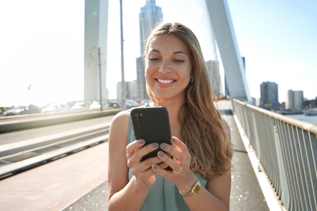 Portrait of young entrepreneur using smartphone on modern bridge in Rotterdam Netherlands