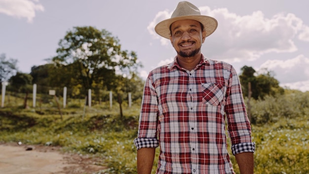 Portrait of young farmer man in the casual shirt and hat in the farm