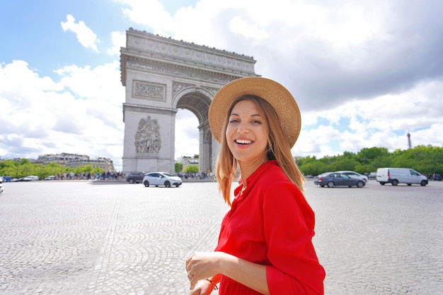 Portrait of young fashion woman walking in Paris with Arc de Triomphe France