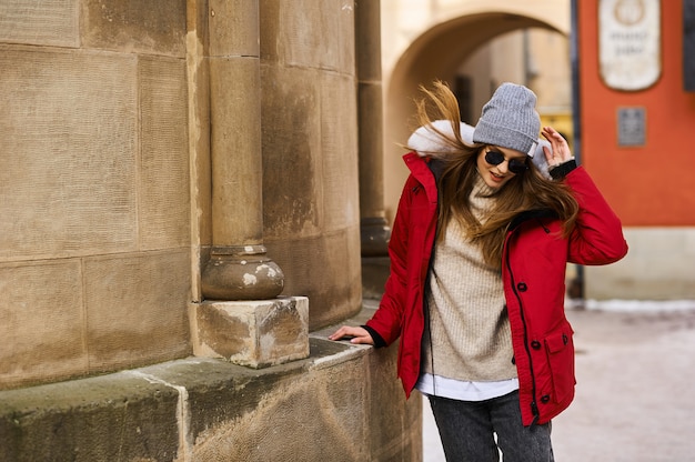 Portrait of a young fashionable girl walking on the street of the city in winter time