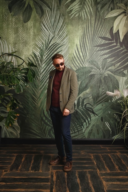 Portrait of young fashionable man, in sunglasses, olive jacket Hipster style guy looking at camera