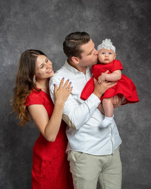 Portrait of a young father and mother holding their little daughter in their arms Studio shooting