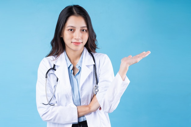 Portrait of young female doctor, isolated on blue background