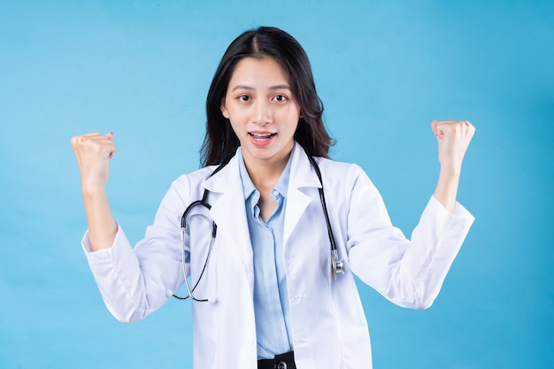 Portrait of young female doctor, isolated on blue background