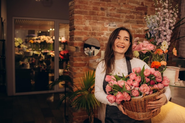 Portrait of young female florist with red tulips looking at camera